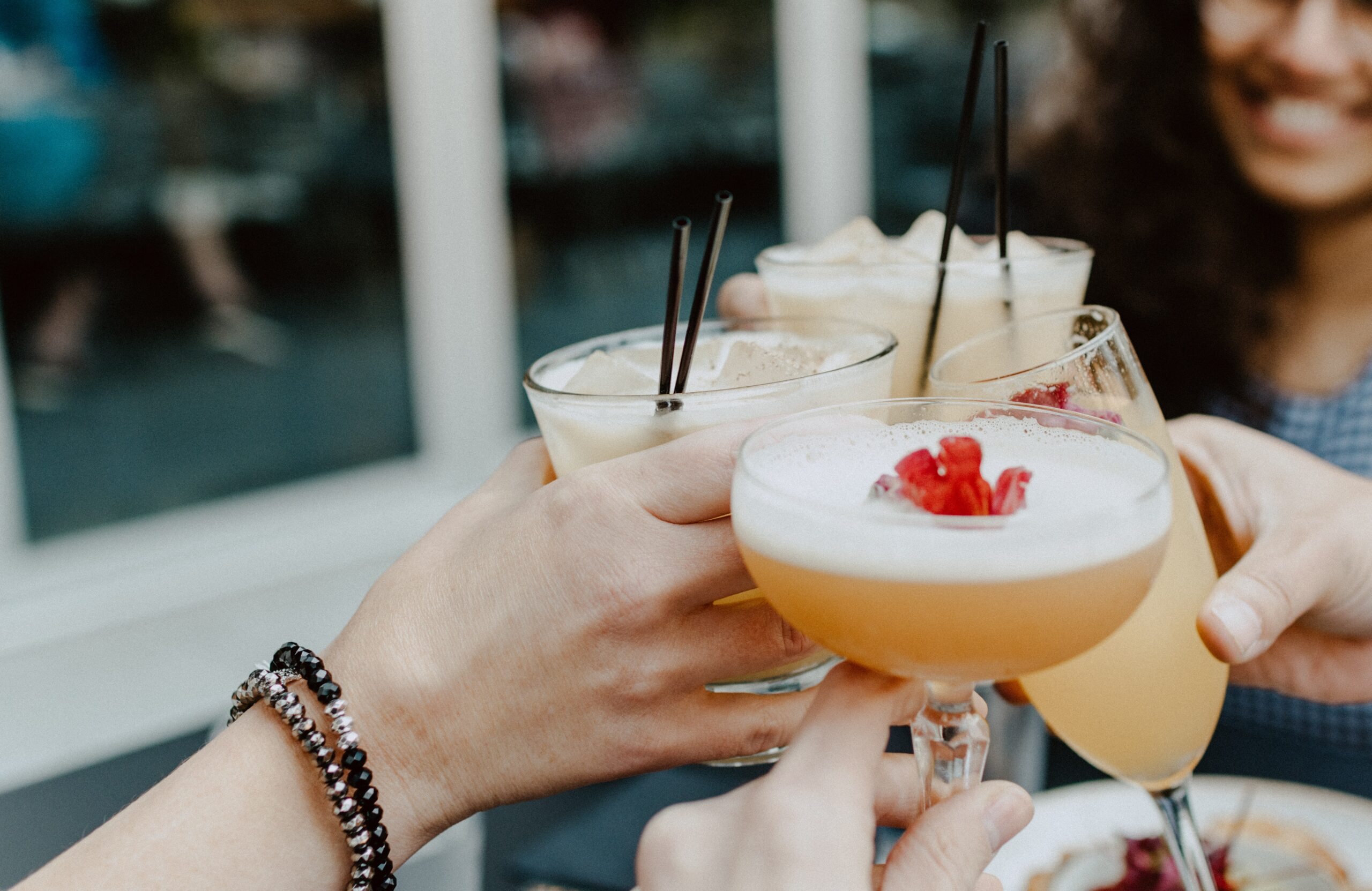 people toasting cocktails at bar