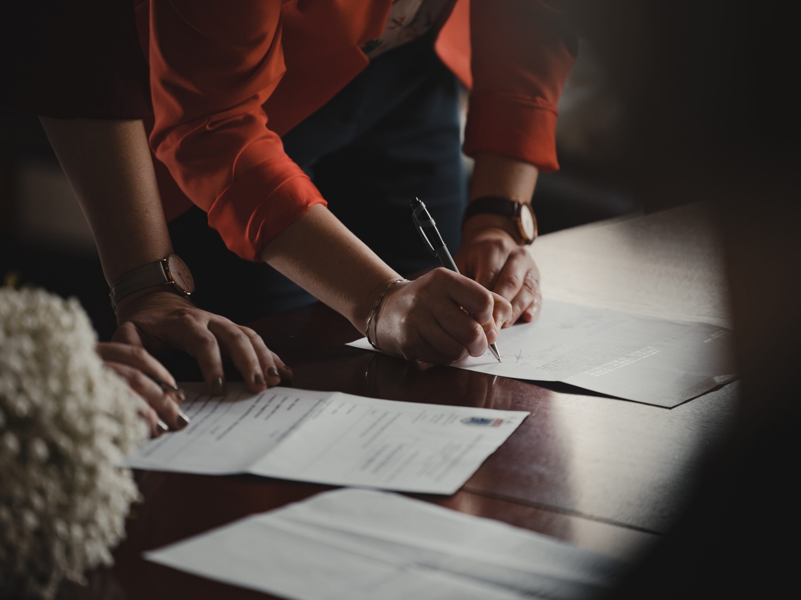 people signing documents on table