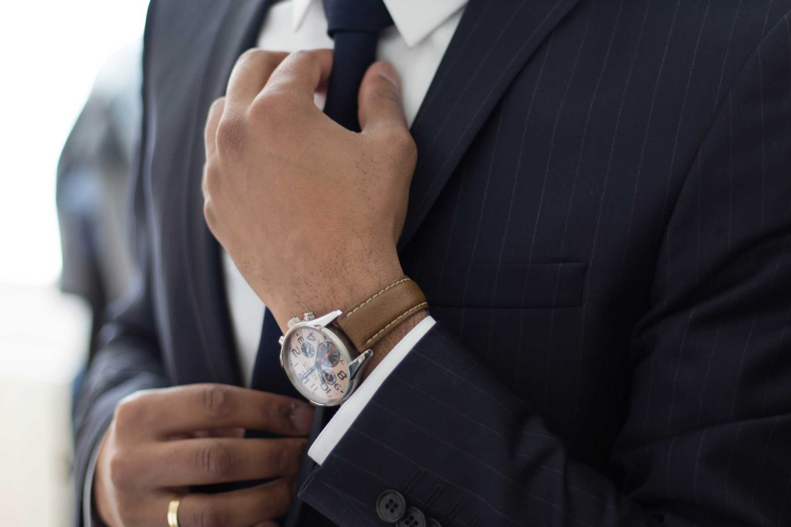 lawyer wearing suit and watch adjusting his tie