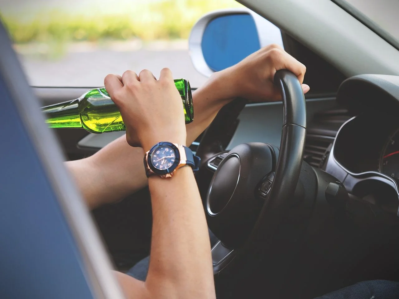 man drinking beer while driving car