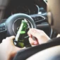 man opening beer bottle while driving