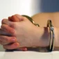 Hands in handcuffs on table
